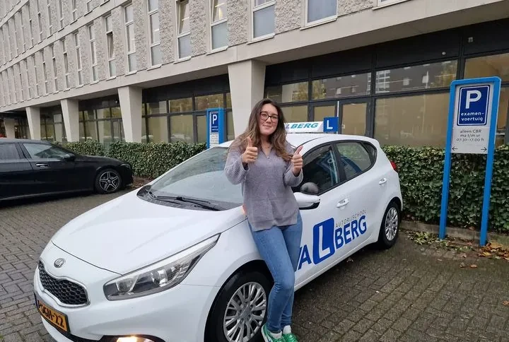 Trotse geslaagde leerling bij de blauwe lesauto van Valberg